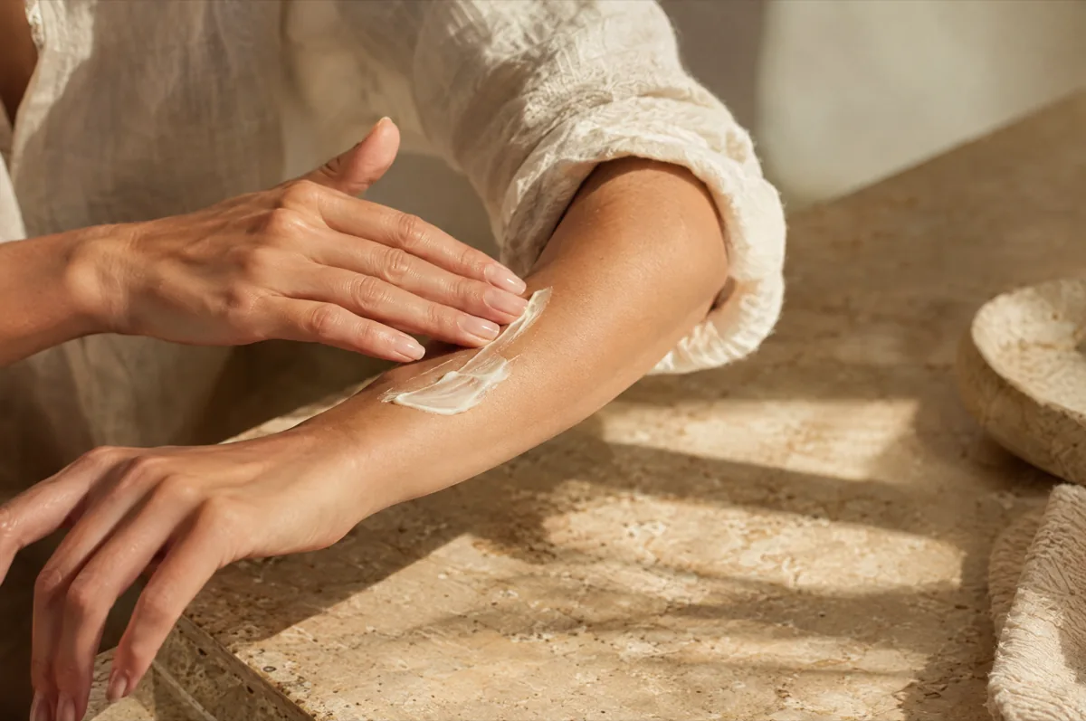 Manos aplicando crema facial durante un ritual de skincare — imagen conceptual de marca